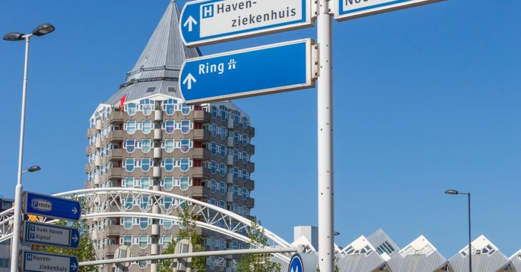 View of street signs with iconic Rotterdam architecture in the background, featuring Cube Houses and Pencil Building.
